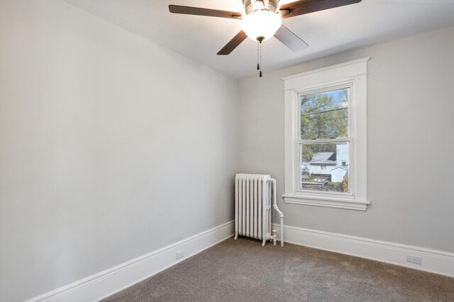 spare room featuring radiator heating unit, carpet, baseboards, and a ceiling fan