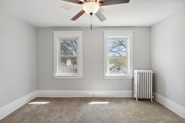 carpeted spare room with radiator, a ceiling fan, and baseboards