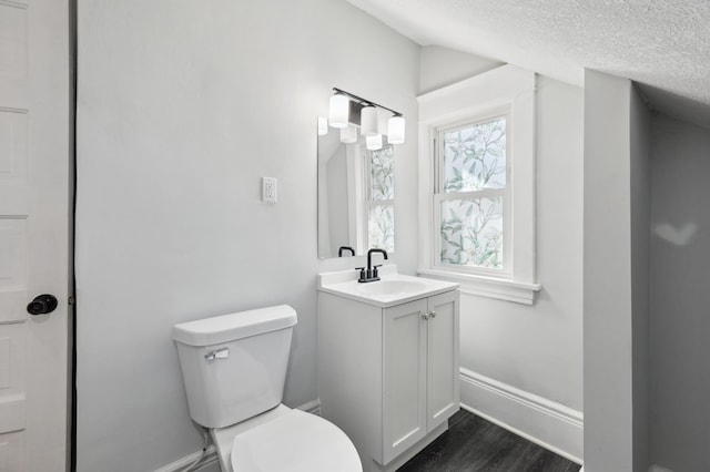 bathroom with toilet, baseboards, wood finished floors, vanity, and a textured ceiling
