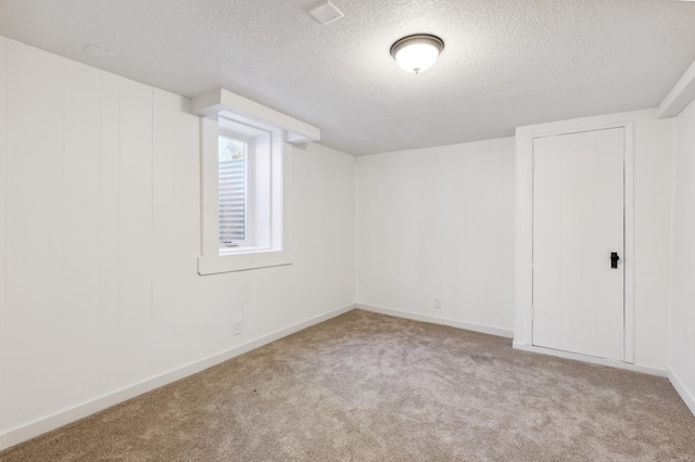basement featuring carpet floors, a textured ceiling, and baseboards