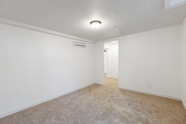 unfurnished room featuring a textured ceiling, carpet flooring, a wall mounted air conditioner, and baseboards