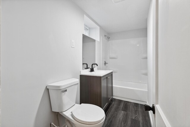 bathroom featuring wood finished floors, toilet,  shower combination, and vanity