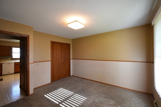536 3rd Ave, Wanamingo, MN 55983 - spare room with a wainscoted wall, baseboards, light carpet, and a baseboard radiator