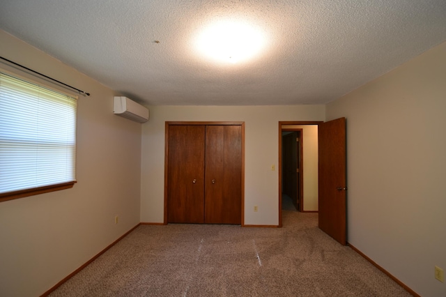 536 3rd Ave, Wanamingo, MN 55983 - unfurnished bedroom featuring a wall mounted air conditioner, a closet, carpet flooring, a textured ceiling, and baseboards