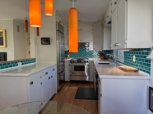 kitchen with high quality appliances, a sink, dark wood-type flooring, decorative backsplash, and light countertops