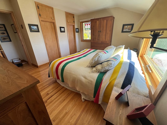 bedroom with light wood finished floors and vaulted ceiling