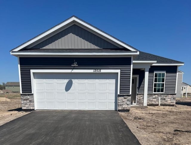 12515 Erskin St NE, Blaine, MN 55449 - view of front of property featuring stone siding, driveway, an attached garage, and a shingled roof
