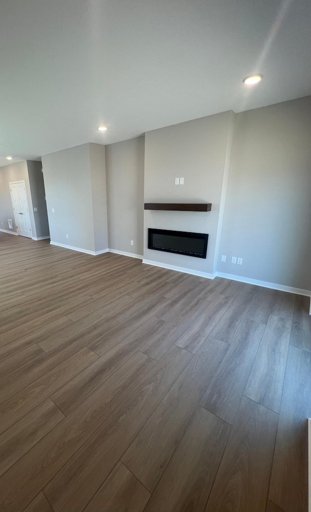 12515 Erskin St NE, Blaine, MN 55449 - unfurnished living room featuring dark wood-type flooring, a glass covered fireplace, baseboards, and recessed lighting