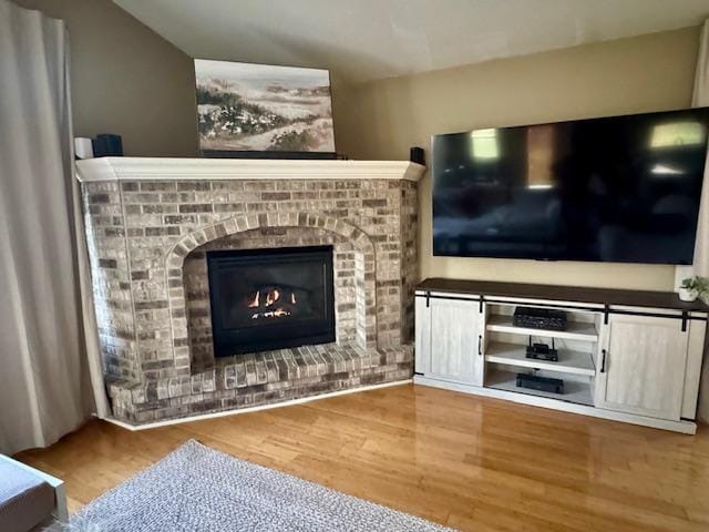 living room featuring wood finished floors and a brick fireplace