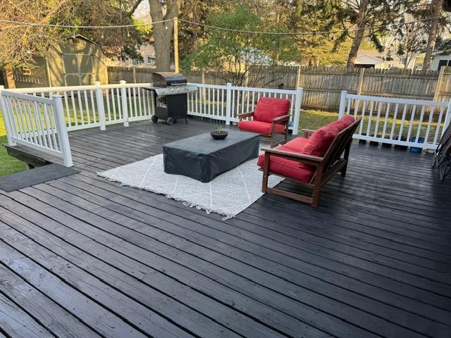 deck with an outdoor hangout area, a fenced backyard, area for grilling, a shed, and an outbuilding