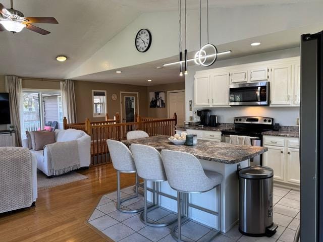 kitchen featuring appliances with stainless steel finishes, white cabinetry, a breakfast bar, ceiling fan, and open floor plan