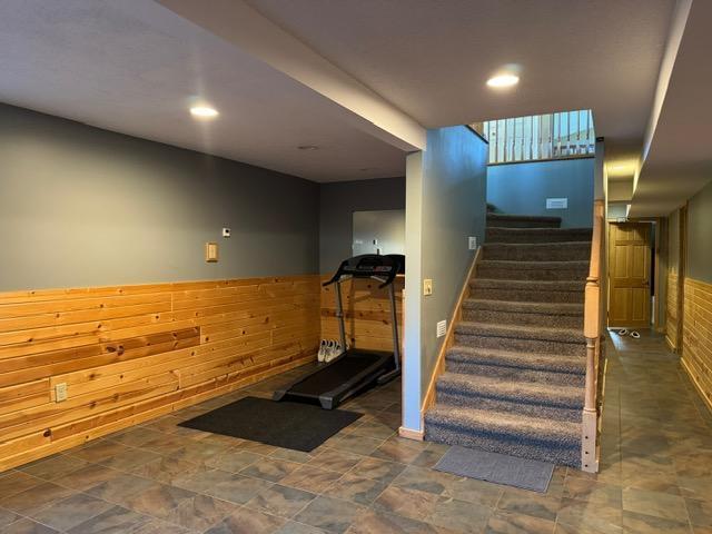 stairs featuring wooden walls, a wainscoted wall, and recessed lighting