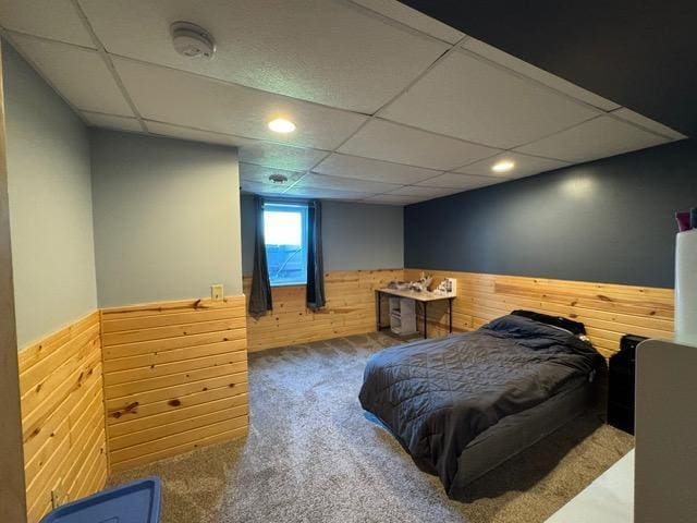 carpeted bedroom with a wainscoted wall, wooden walls, a paneled ceiling, and recessed lighting
