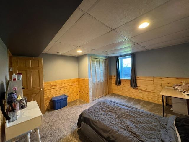 bedroom with wainscoting, wooden walls, carpet, recessed lighting, and a drop ceiling