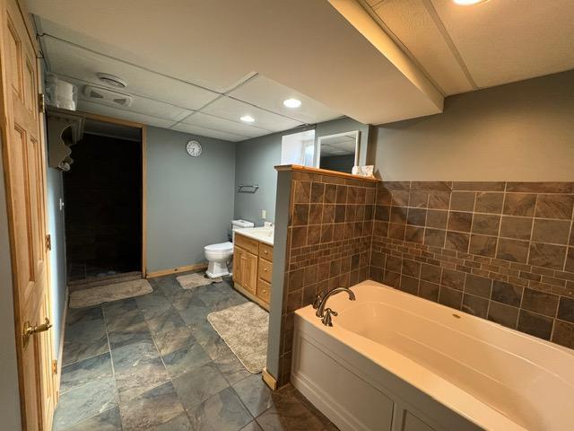 full bathroom featuring vanity, a garden tub, toilet, and recessed lighting