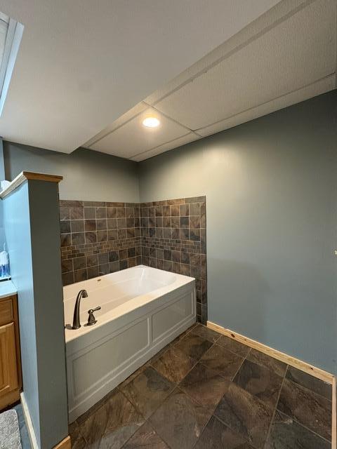 full bathroom featuring a garden tub, baseboards, and vanity