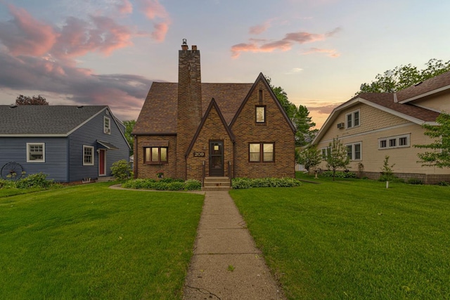 209 Main St, Arlington, MN 55307 - tudor-style house featuring brick siding, a front lawn, and a chimney