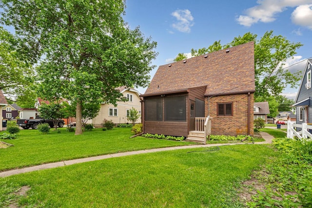 209 Main St, Arlington, MN 55307 - back of house featuring brick siding, a sunroom, a yard, and roof with shingles
