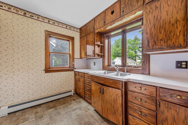 209 Main St, Arlington, MN 55307 - kitchen featuring a sink, a baseboard heating unit, wallpapered walls, light countertops, and stone finish flooring