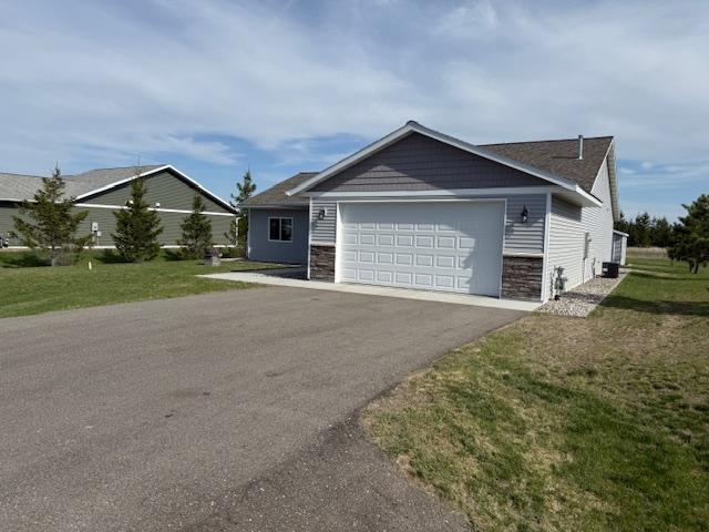 2008 Whiting Rd NW Unit 26, Bemidji, MN 56601 - view of front of house featuring driveway, an attached garage, a front lawn, and stone siding