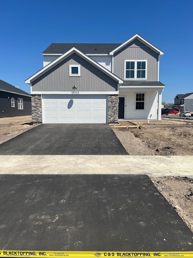 12608 Erskin St NE, Blaine, MN 55449 - view of front of house with stone siding, asphalt driveway, board and batten siding, and a garage