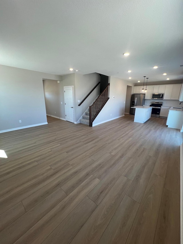 12608 Erskin St NE, Blaine, MN 55449 - unfurnished living room featuring baseboards, a sink, light wood-type flooring, stairs, and recessed lighting