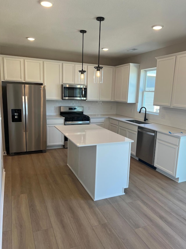 12608 Erskin St NE, Blaine, MN 55449 - kitchen with stainless steel appliances, a sink, wood finished floors, white cabinets, and recessed lighting