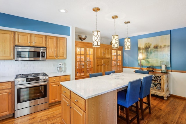 7676 Woodview Ct, Edina, MN 55439 - kitchen with appliances with stainless steel finishes, a center island, light countertops, and backsplash