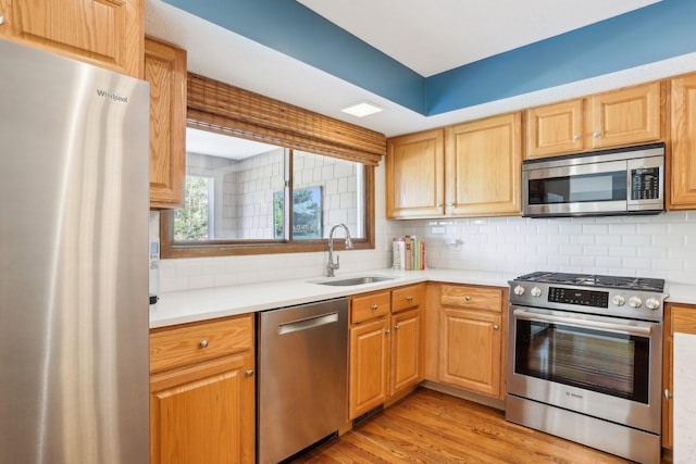7676 Woodview Ct, Edina, MN 55439 - kitchen featuring appliances with stainless steel finishes, a sink, tasteful backsplash, light countertops, and light wood-type flooring
