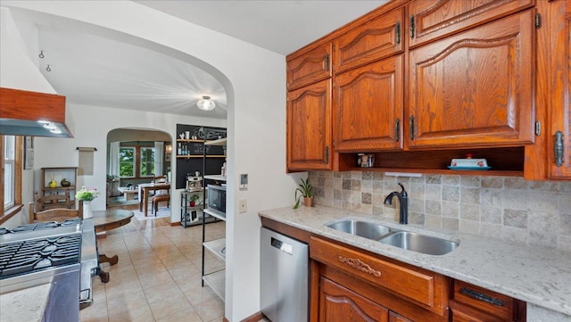 12586 220th St, Silver Lake, MN 55381 - kitchen featuring arched walkways, appliances with stainless steel finishes, backsplash, light stone countertops, and light tile patterned floors