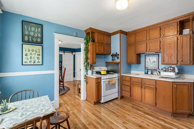 1123 5th St NE, Minneapolis, MN 55413 - kitchen featuring white gas range, a sink, light countertops, and brown cabinets