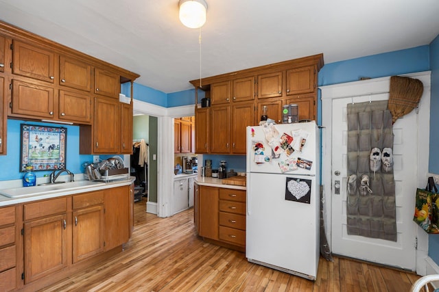 1123 5th St NE, Minneapolis, MN 55413 - kitchen featuring freestanding refrigerator, a sink, brown cabinetry, and light countertops