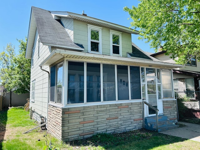 1536 Concordia Ave, Saint Paul, MN 55104 - view of side of property with a sunroom, a shingled roof, entry steps, and stone siding