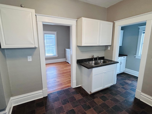 1536 Concordia Ave, Saint Paul, MN 55104 - kitchen with a sink, baseboards, dark countertops, and white cabinets