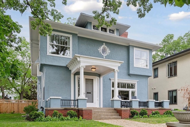 view of front of home featuring fence, covered porch, and stucco siding