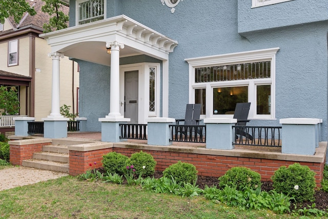 doorway to property featuring covered porch and stucco siding