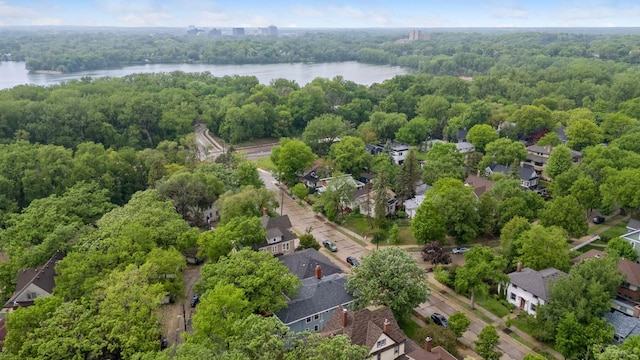 aerial perspective of suburban area featuring a nearby body of water and a heavily wooded area