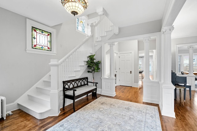 foyer with decorative columns, stairway, and wood finished floors