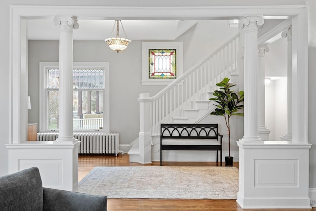entryway with radiator, wood finished floors, stairway, and baseboards