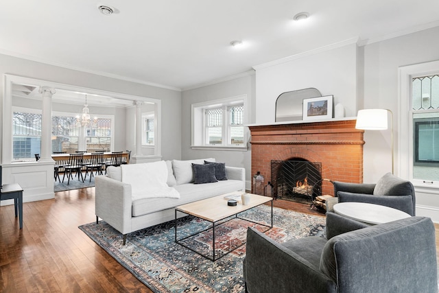 living area with hardwood / wood-style floors, crown molding, a fireplace, and ornate columns