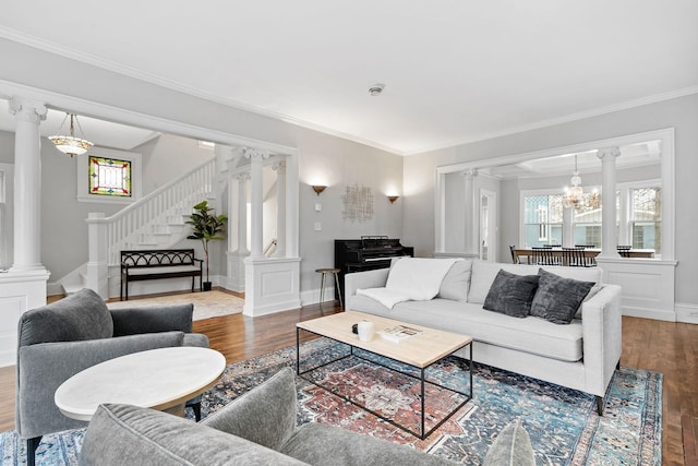 living room with decorative columns, wood finished floors, stairway, ornamental molding, and a chandelier
