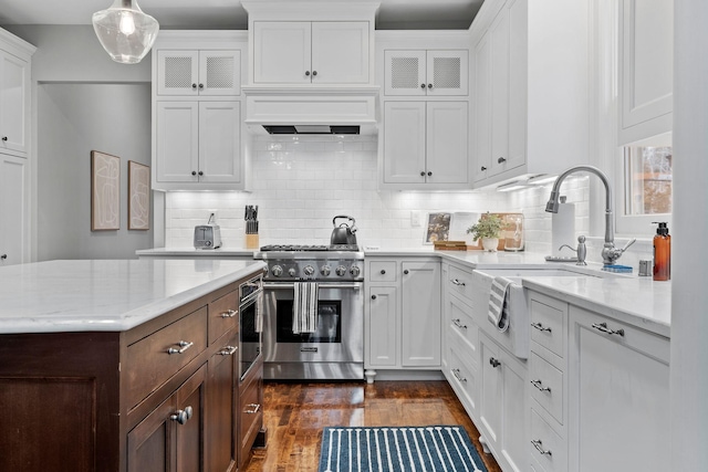 kitchen featuring high end stove, a sink, white cabinetry, and glass insert cabinets