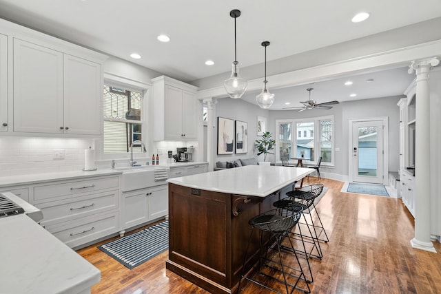 kitchen with a sink, decorative backsplash, a ceiling fan, a kitchen bar, and light countertops