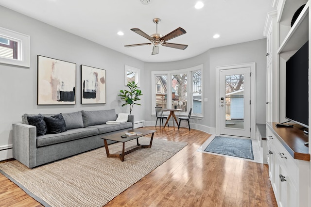 living area featuring light wood-type flooring, ceiling fan, recessed lighting, a baseboard radiator, and baseboards