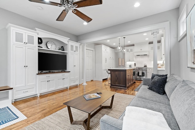 living area featuring light wood-style flooring, a ceiling fan, recessed lighting, and decorative columns