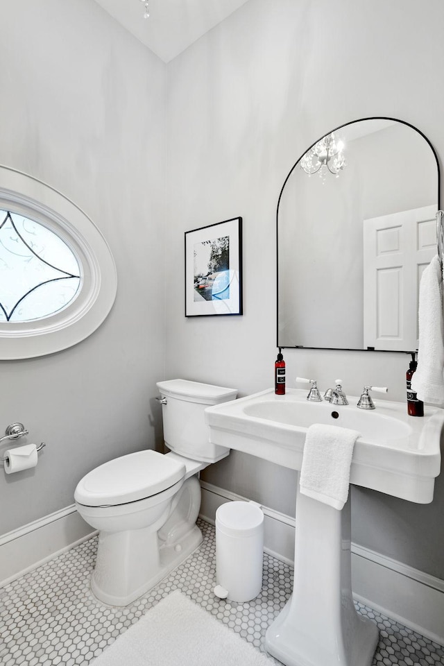 half bath with toilet, tile patterned floors, and baseboards