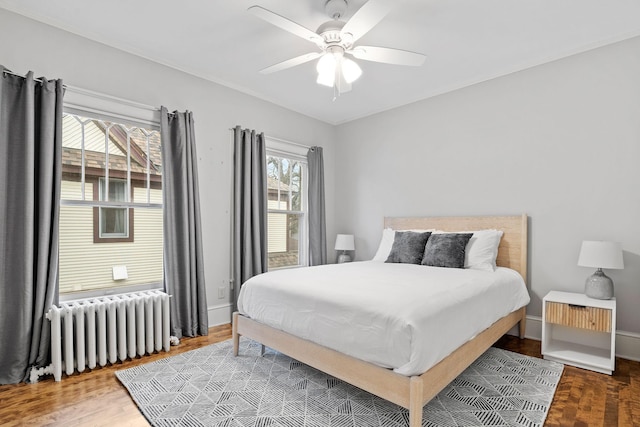 bedroom with radiator, baseboards, ceiling fan, and wood finished floors