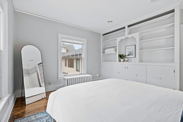 bedroom with radiator, ornamental molding, and wood finished floors