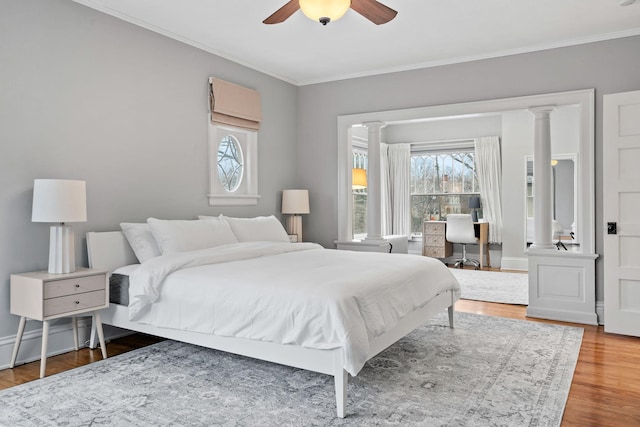 bedroom featuring ornamental molding, wood finished floors, an office area, ceiling fan, and ornate columns
