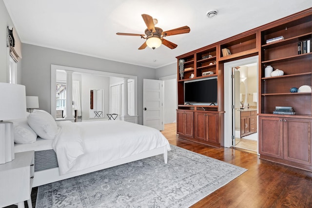 bedroom featuring dark wood-type flooring, crown molding, and ensuite bathroom